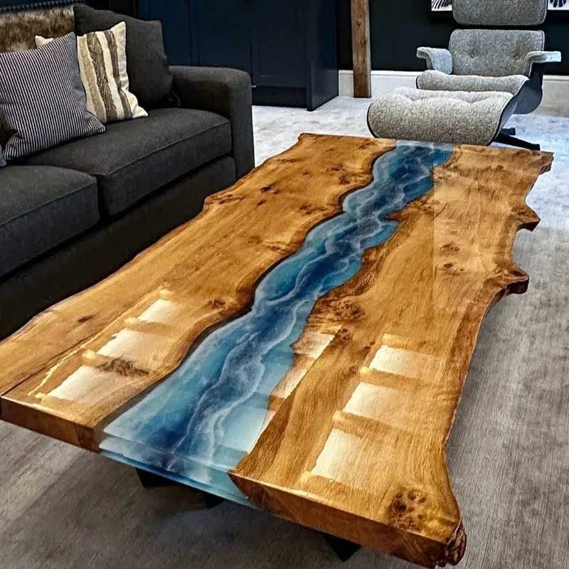 Table basse rivière en bois clair et résine bleue devant un canapé